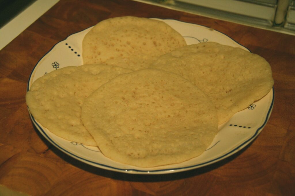 Baghrir disposés sur une assiette, surface parsemée de petits trous.