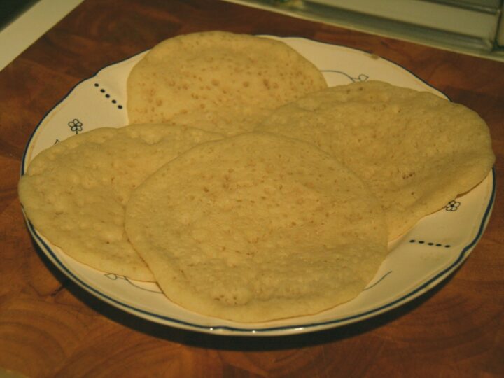Baghrir disposés sur une assiette, surface parsemée de petits trous.
