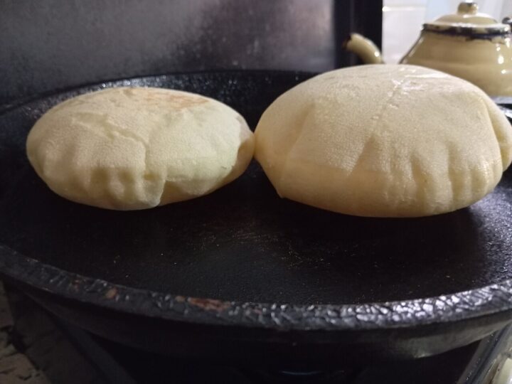 Deux batbouts gonflés pendant leur cuisson sur une plaque