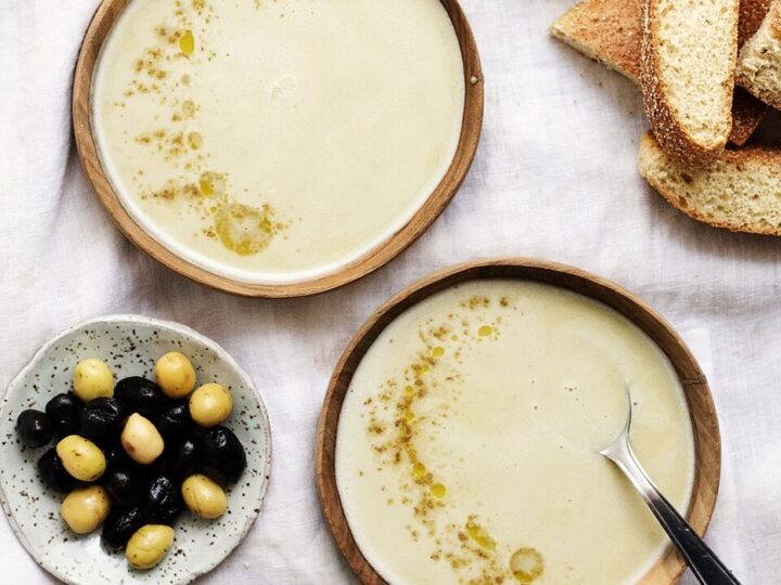 Deux bols de bissara, avec olives, épices et pain à côté.