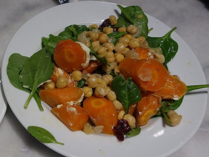Assiette de carottes en rondelles avec légumineuses et feuilles vertes.