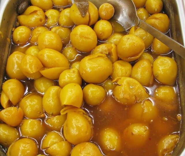 Petits citrons marocains conservés, présentés dans un grand récipient avec leur liquide.