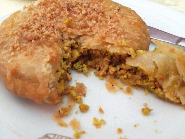 Pastilla au poulet ouverte, montrant la garniture sous une croûte dorée.