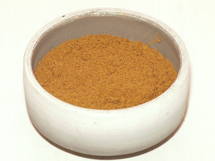 Bol de ras el-hanout marocain en poudre, de couleur ocre.