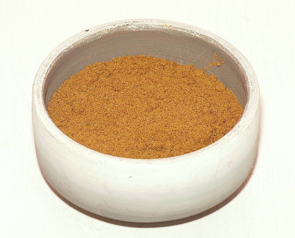 Bol de ras el-hanout marocain en poudre, de couleur ocre.