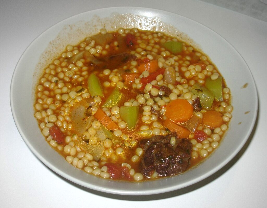 Assiette de berkoukes avec des légumes et du bouillon.