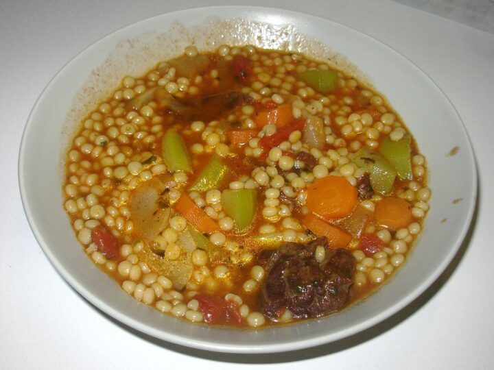 Assiette de berkoukes avec des légumes et du bouillon.
