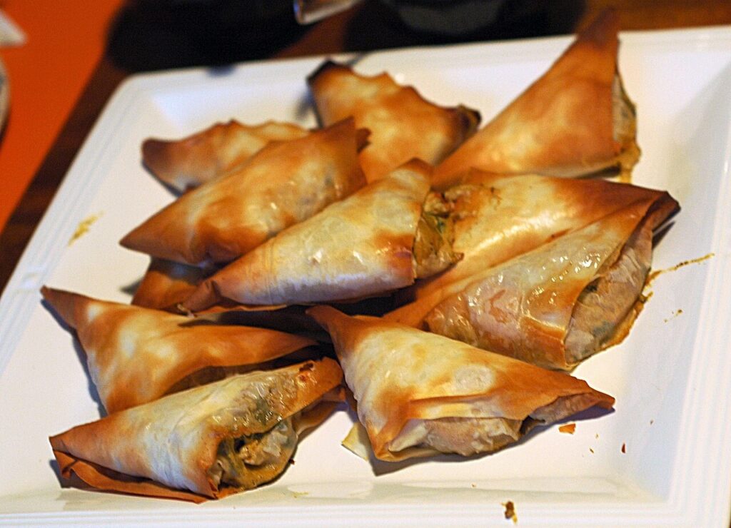 Briouates triangulaires dorées présentées sur une assiette.