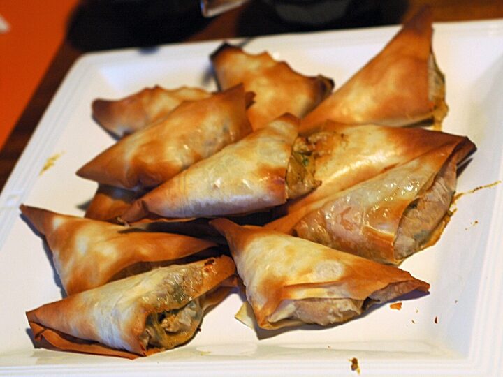 Briouates triangulaires dorées présentées sur une assiette.