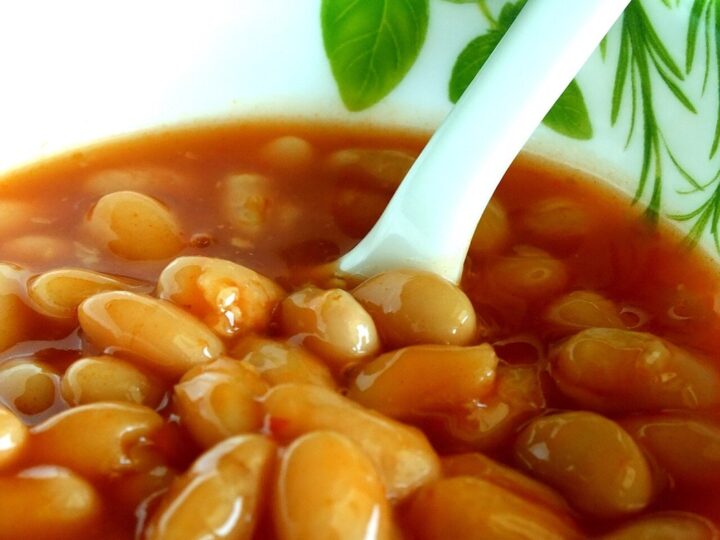 Haricots blancs cuits dans une sauce tomate, avec une cuillère dans le bol.