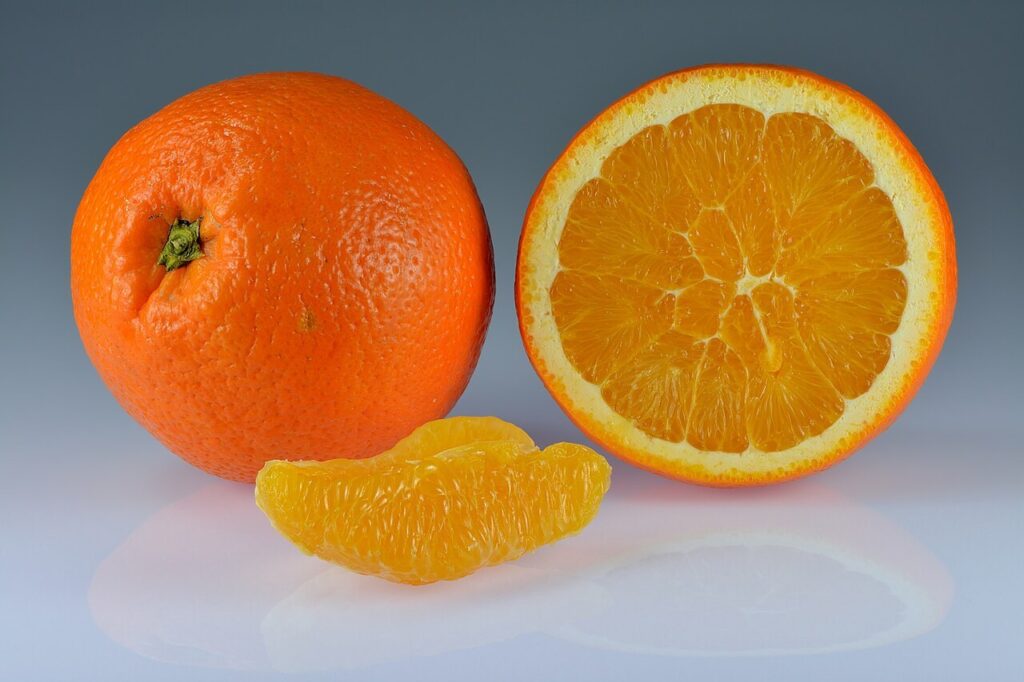 Oranges entières, demi-orange et quartier présentés sur fond clair.